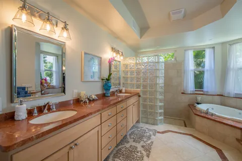 a spacious bathroom with double vanity sink a mirror a lamp and window