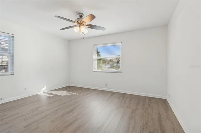 a view of empty room with wooden floor and fan