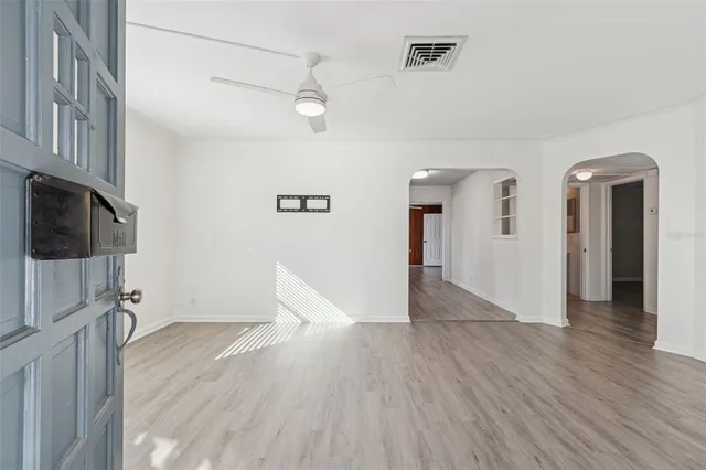 a view of a hallway with wooden floor and a bathroom