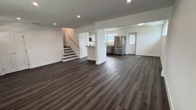 a view of an empty room with wooden floor and closet