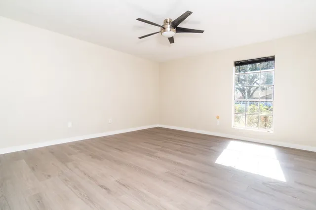 an empty room with wooden floor and windows