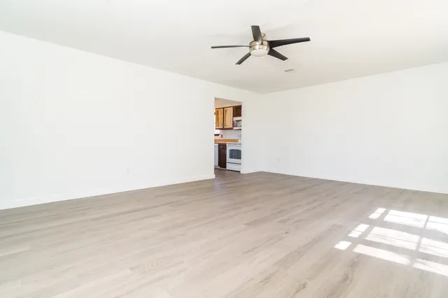 a view of a kitchen with a sink a stove top oven and wooden floor
