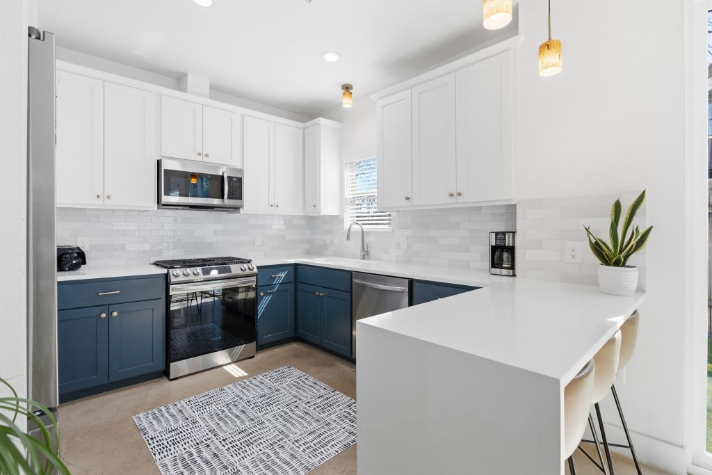 3112 Powell Circle Austin, TX 78704 - Photo 8 of 27 Kitchen featuring a kitchen breakfast bar, a peninsula, two tone color scheme, stainless steel appliances, and pendant lighting