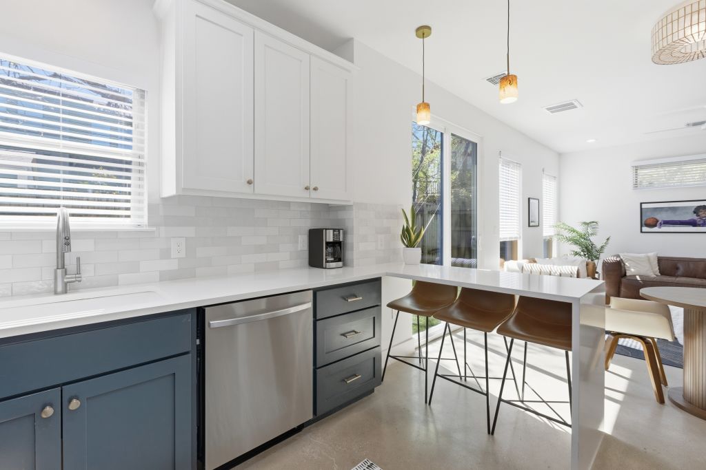 3112 Powell Circle Austin, TX 78704 - Photo 25 of 27 Two tone kitchen with two tone cabinets, concrete flooring, dishwasher, open floor plan, and pendant lighting