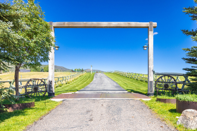 6117 North Rocky Ridge Road Peoa, UT 84061 - Photo 1 of 82 Gated entry with a substantial wood archway and integrated lanterns