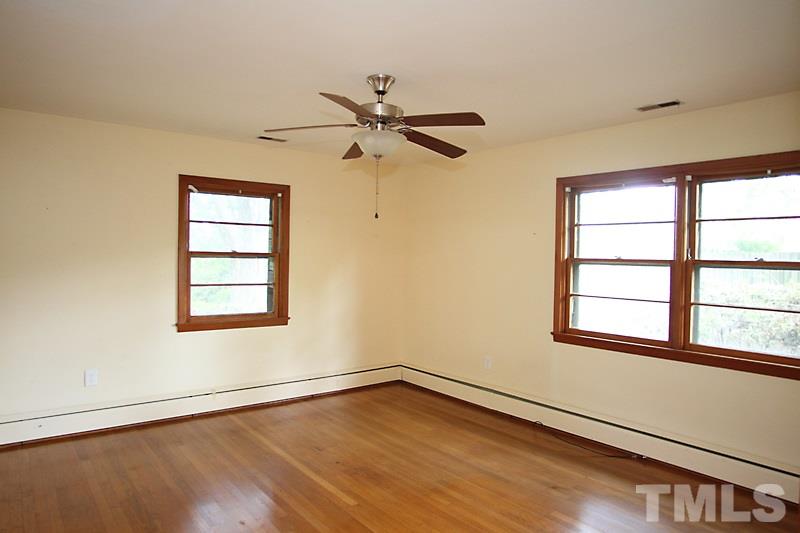 313 Loop Road Garner, NC 27529 - Photo 9 of 12 an empty room with wooden floor fan and windows