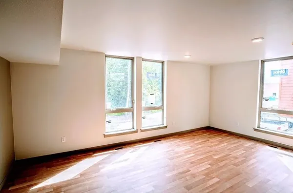 a view of an empty room with wooden floor and a window