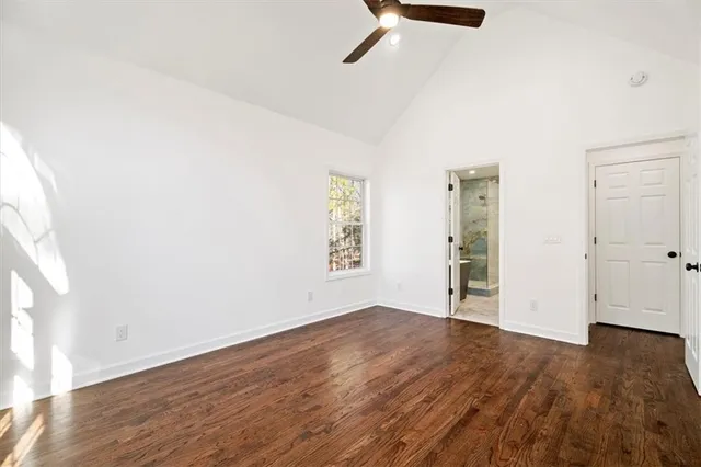 an empty room with wooden floor closet and windows