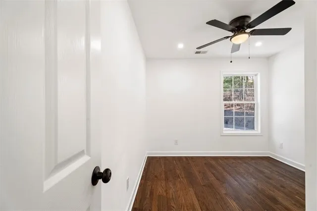 an empty room with wooden floor fan and windows