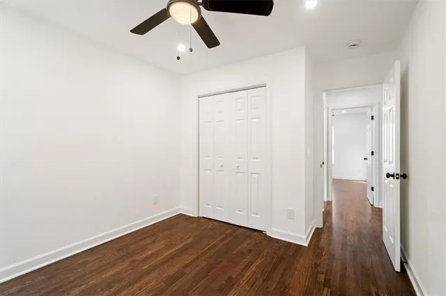 an empty room with wooden floor and a ceiling fan