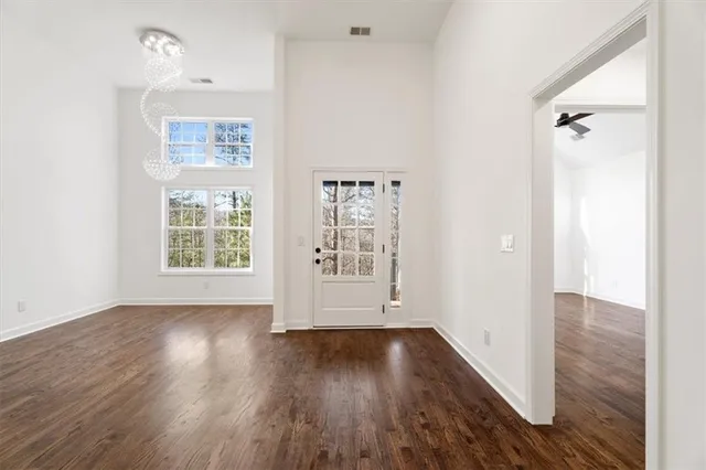 an empty room with wooden floor and windows