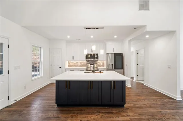 a room with kitchen island a sink wooden floor and a refrigerator