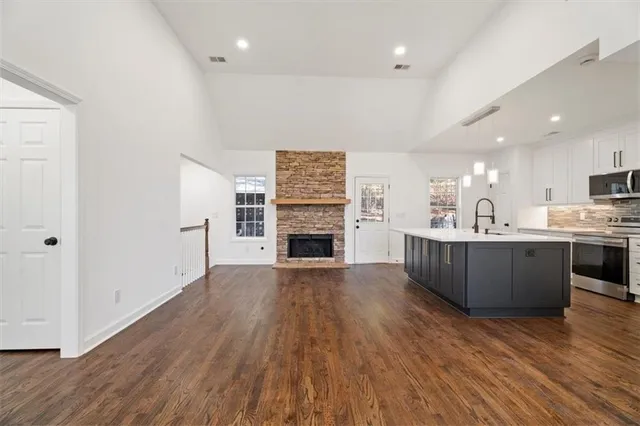 a open kitchen with a refrigerator a stove top oven and wooden floor