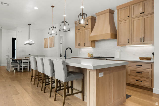 5354 Cyan Lane St. George, UT 84790 - Photo 3 of 45 Kitchen with light wood-style floors, light wood finish cabinetry, and a kitchen bar