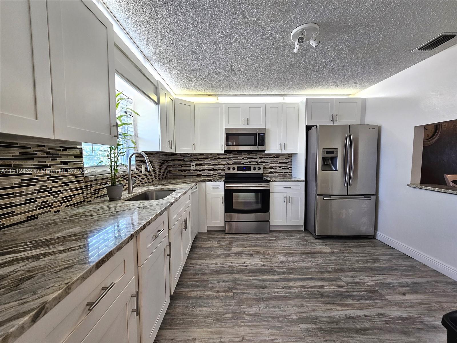 a large kitchen with cabinets stainless steel appliances a sink and a window
