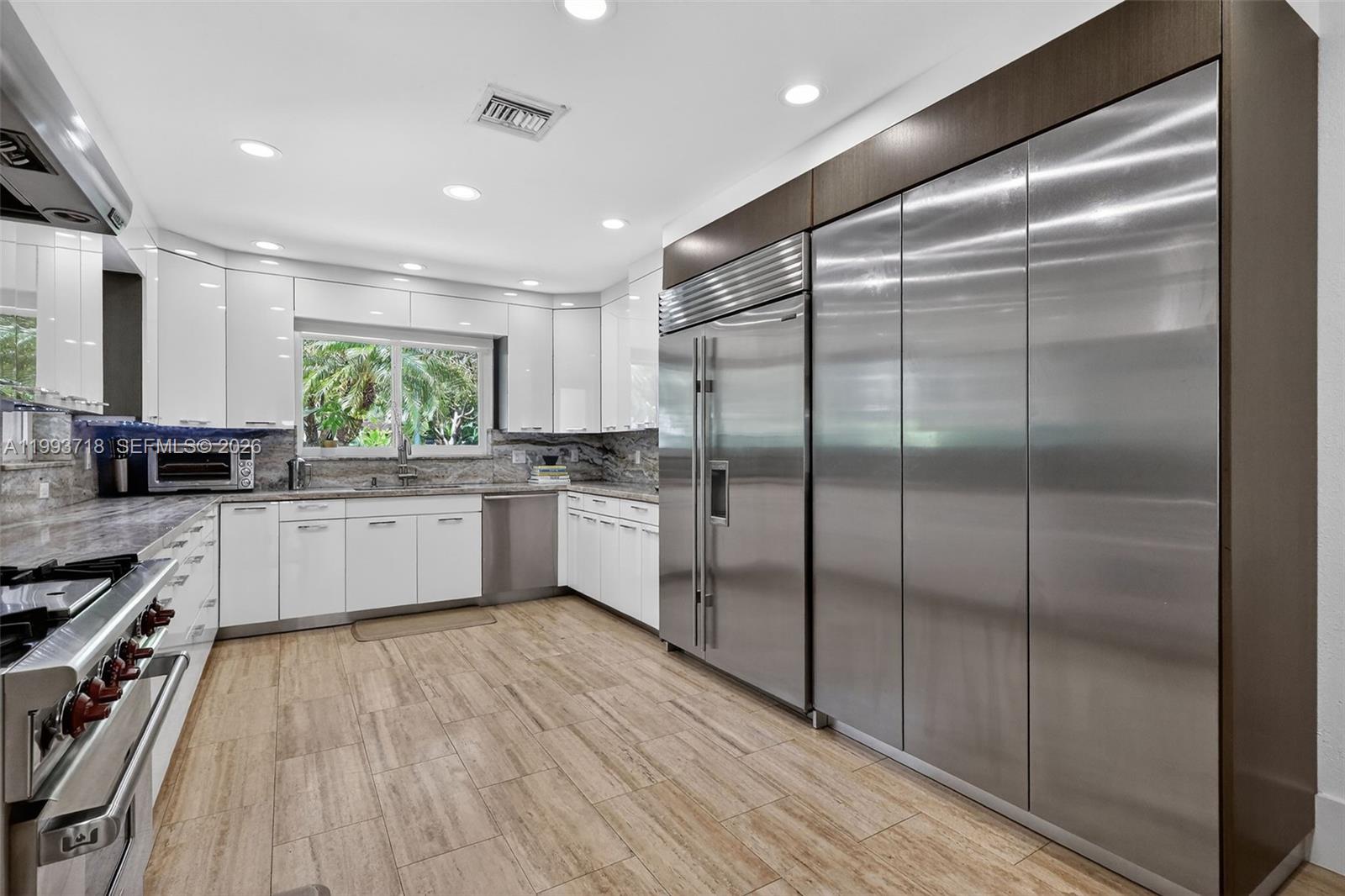 3258 Riviera Drive Coral Gables, FL 33134 - Photo 11 of 43 a kitchen with stainless steel appliances a refrigerator sink and white cabinets