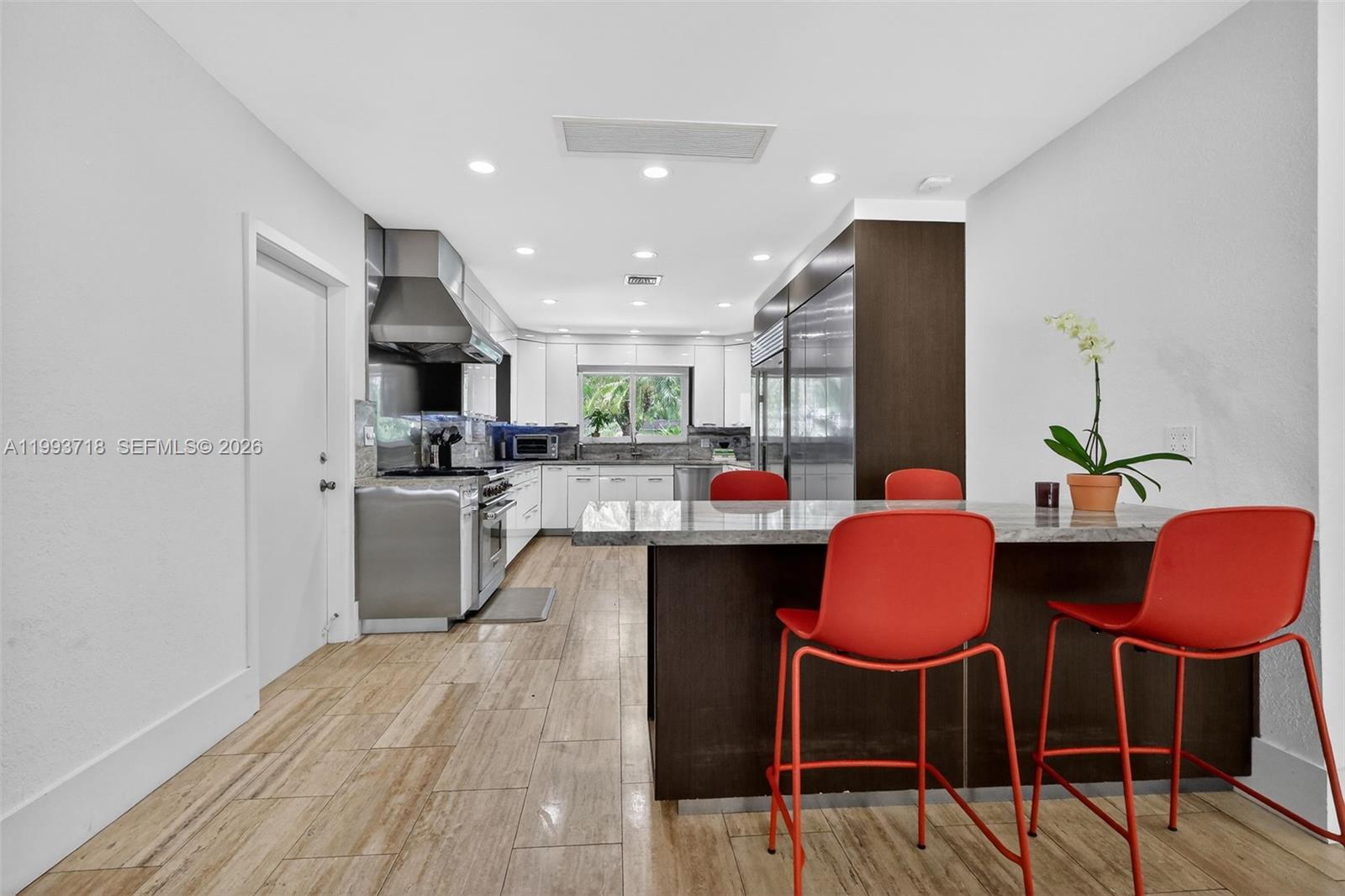3258 Riviera Drive Coral Gables, FL 33134 - Photo 10 of 43 a kitchen with stainless steel appliances a table chairs refrigerator and sink