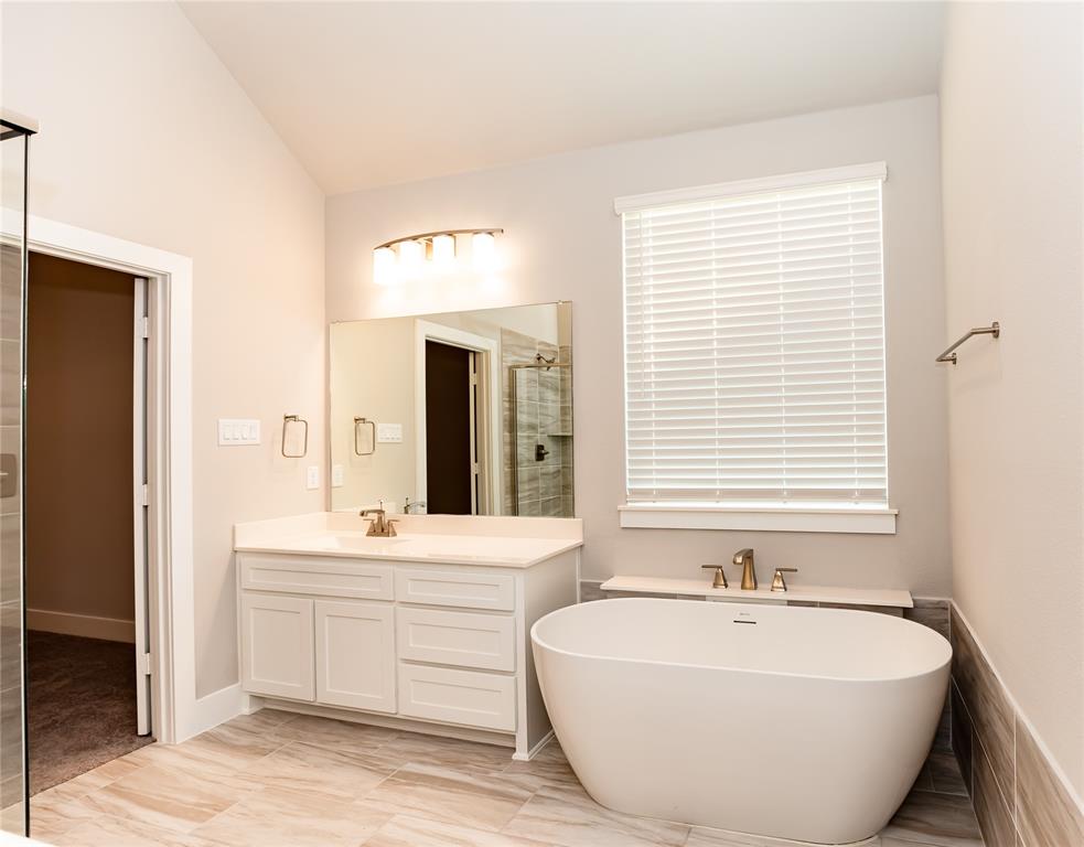6124 Shasta Creek Road Celina, TX 75009 - Photo 11 of 27 a spacious bathroom with double vanity a window a bathtub and a mirror