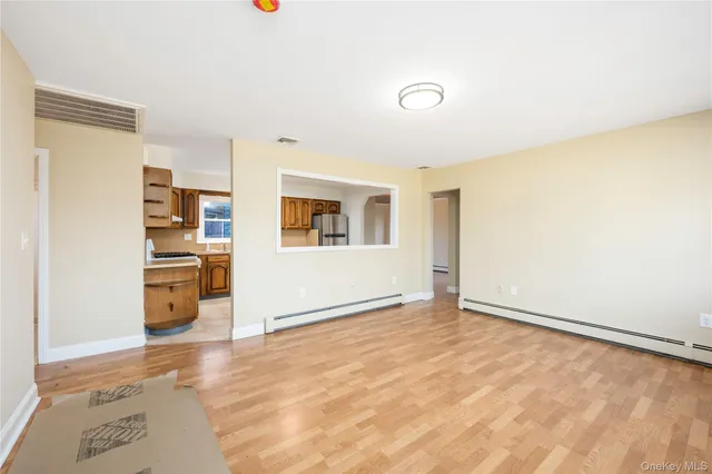 a view of a livingroom with wooden floor and kitchen space