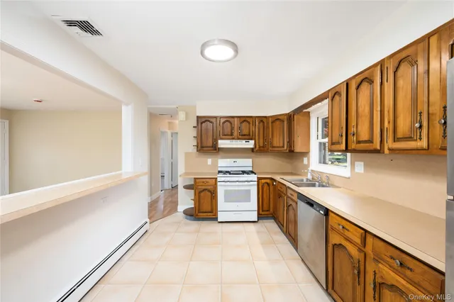 a kitchen with stainless steel appliances granite countertop a stove top oven a sink a counter space and cabinets