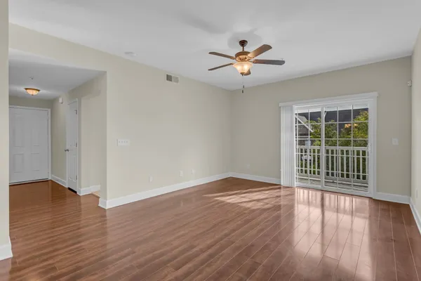a view of an empty room with wooden floor and a window