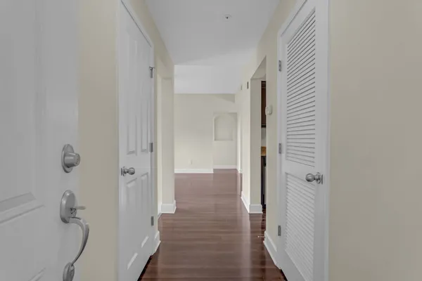 a view of a big room with wooden floor a ceiling fan and windows