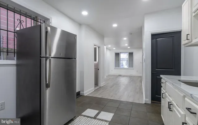 a view of a refrigerator in kitchen and an empty room with windows