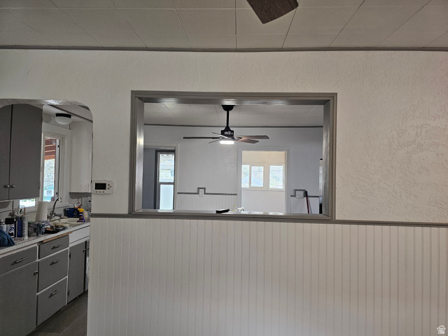 744 Royal Street Helper, UT 84526 - Photo 9 of 33 Kitchen with a ceiling fan, a textured wall, wainscoting, light countertops, and healthy amount of natural light