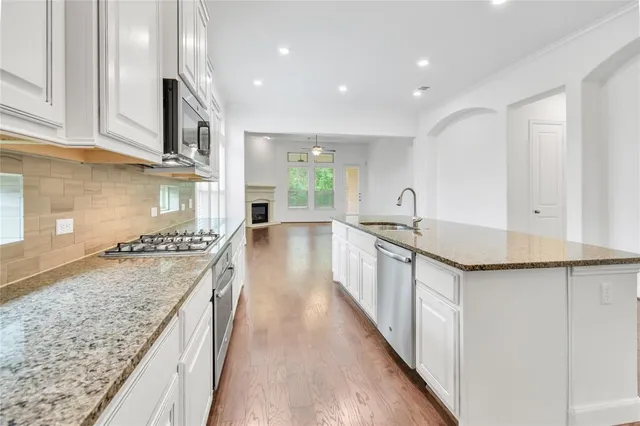 a kitchen with stainless steel appliances granite countertop a sink stove and cabinets