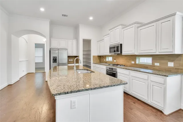 a kitchen with stainless steel appliances granite countertop a sink a stove and a refrigerator