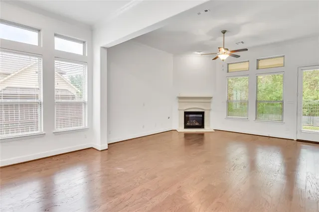 a view of an empty room with wooden floor fireplace and a window