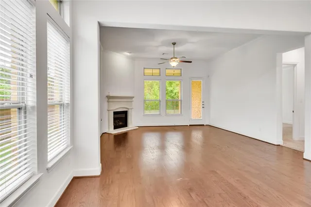 an empty room with wooden floor fireplace and windows