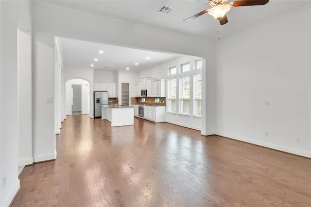 a view of a kitchen with a sink a refrigerator a ceiling fan and wooden floor