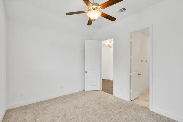 an empty room with closet and a chandelier fan