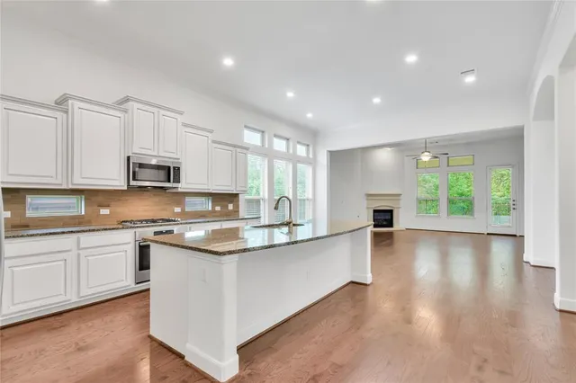 a large kitchen with stainless steel appliances granite countertop a stove and a wooden floors