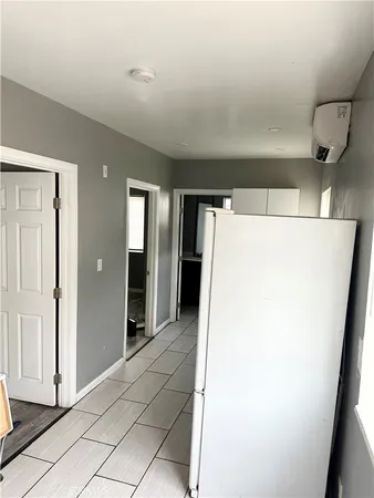 a view of a refrigerator in kitchen and an empty room