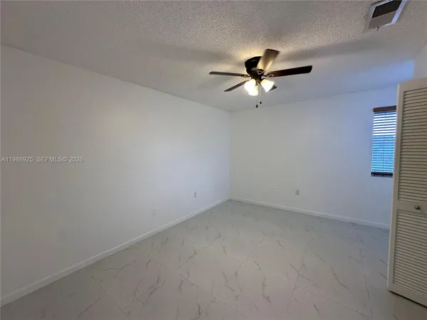 an empty room with closet and a ceiling fan