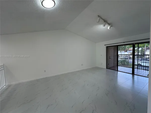 a view of an empty room with wooden floor and windows
