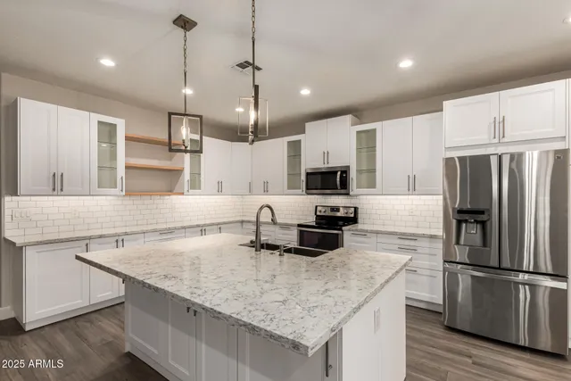 a kitchen with kitchen island a counter space a refrigerator a sink and wooden floor