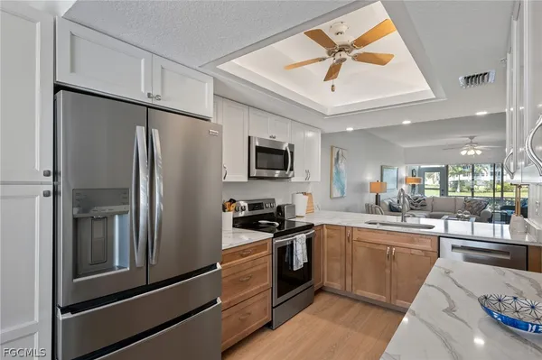 a kitchen with stainless steel appliances granite countertop a refrigerator a sink a stove and white cabinets