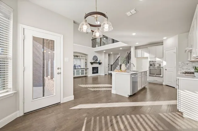 a view of a kitchen with kitchen island stainless steel appliances wooden floor and a chandelier