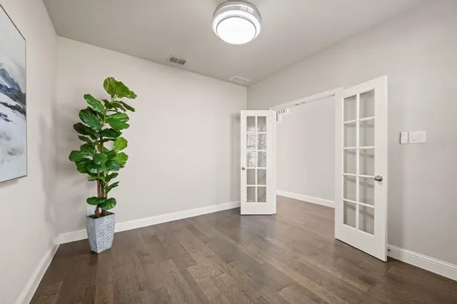 a view of an empty room with wooden floor and a potted plant