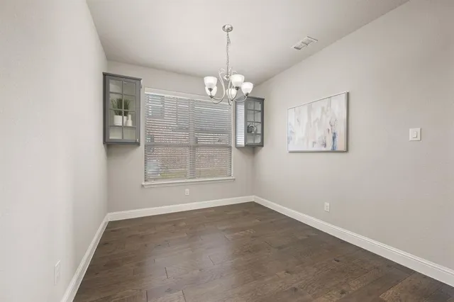 an empty room with chandelier fan and windows