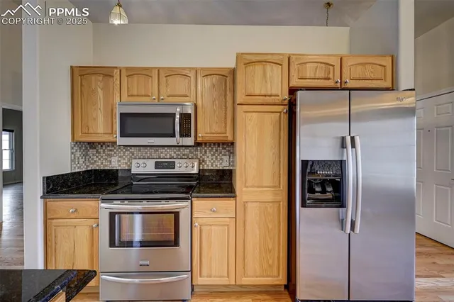 a kitchen with stainless steel appliances granite countertop a refrigerator and a stove top oven