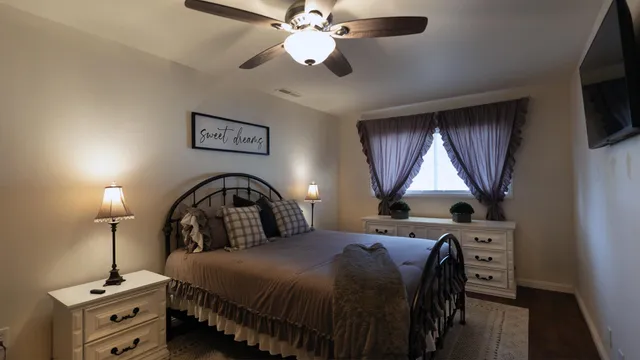 a bedroom with a bed and a flat tv screen on the dresser