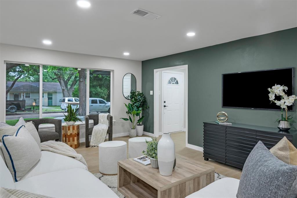 4815 Kelman Street Dallas, TX 75214 - Photo 2 of 37 Spacious living area featuring large windows, recessed ceiling lighting, wood-finish flooring, and a modern accent wall