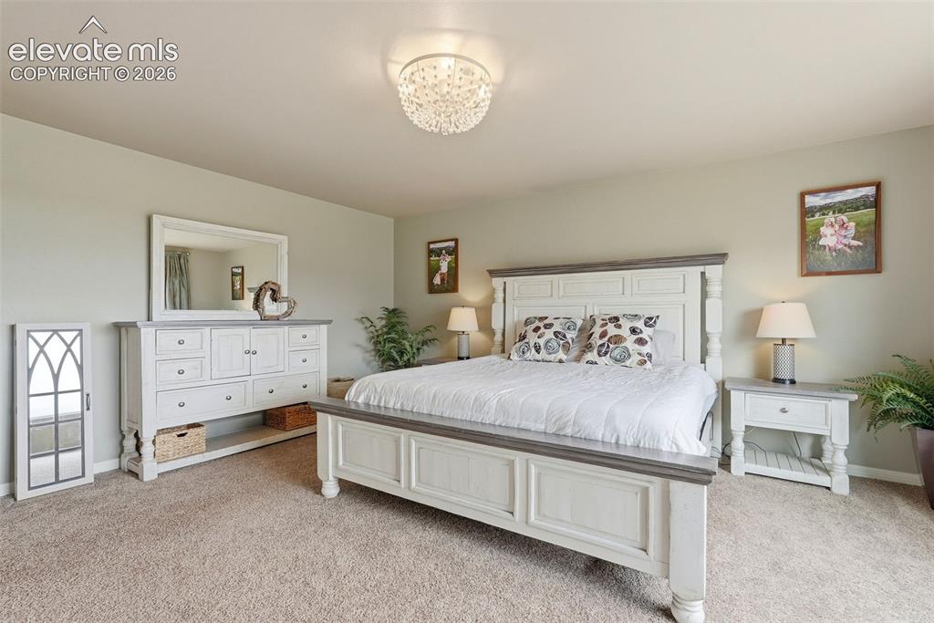 2264 Reed Grass Way Colorado Springs, CO 80915 - Photo 31 of 50 a spacious bedroom with a bed and a lamp on dresser