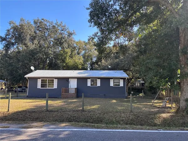 a view of a brick house next to a yard with large trees