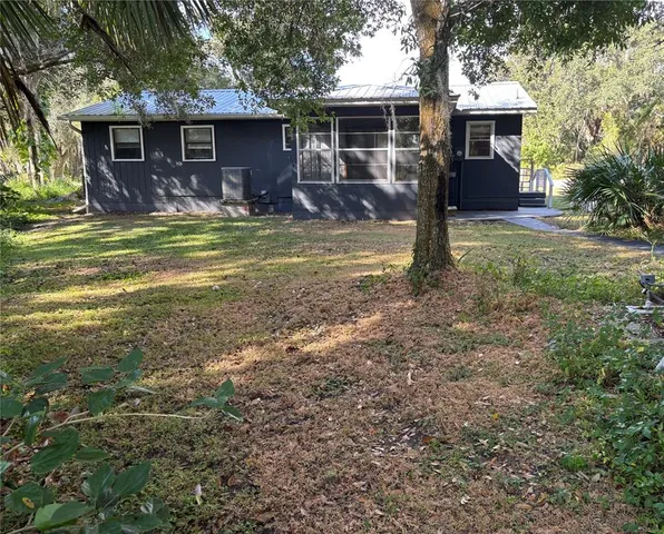 a view of a house with backyard and a tree