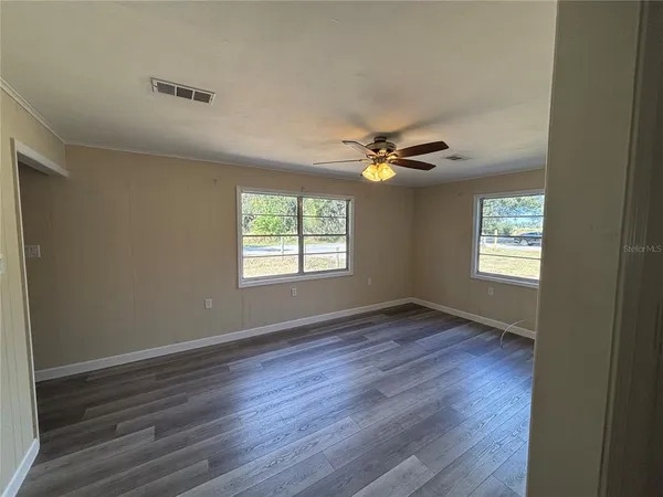 a view of an empty room with a window and wooden floor